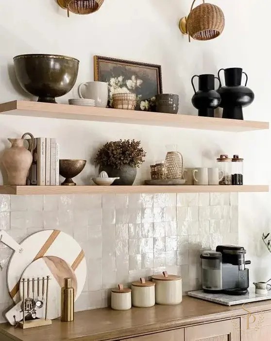 Open shelves styled with collected pottery, books, and a small painting above a zellige tile backsplash
