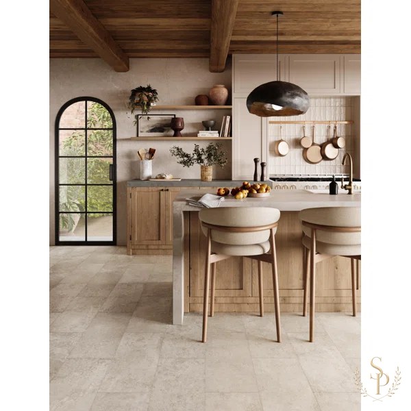 Open kitchen with oak cabinetry, arched steel door, and a pale stone island